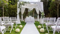 Setup of an outdoor wedding ceremony with white chairs.