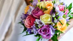 Woman in white wedding dress holding colorful bouquet.